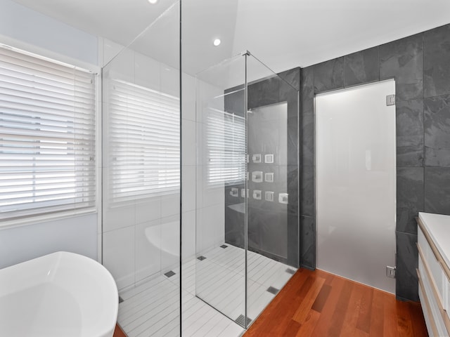 bathroom with tile walls, vanity, and walk in shower