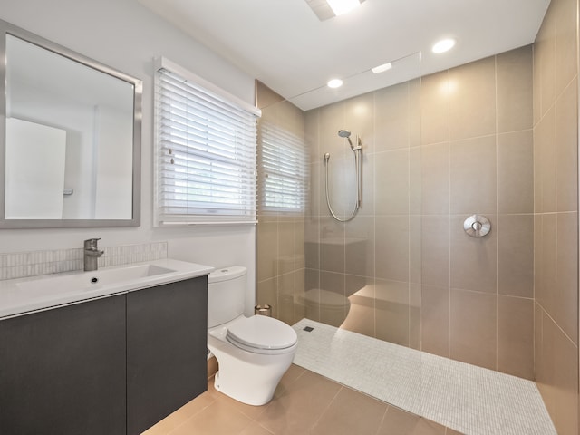 bathroom featuring vanity, a tile shower, tile patterned floors, and toilet