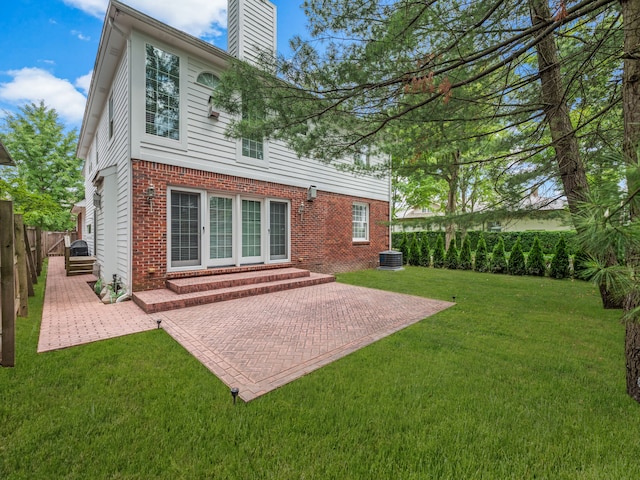 rear view of property featuring a patio area, central air condition unit, and a lawn