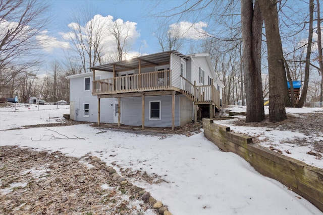 snow covered back of property featuring a wooden deck