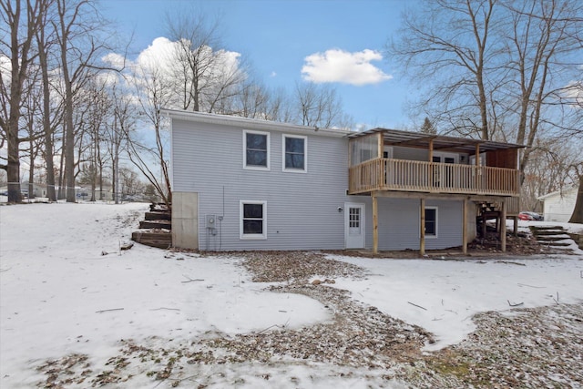 snow covered back of property with a wooden deck