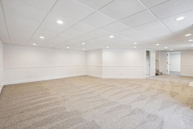 basement with a paneled ceiling and light carpet