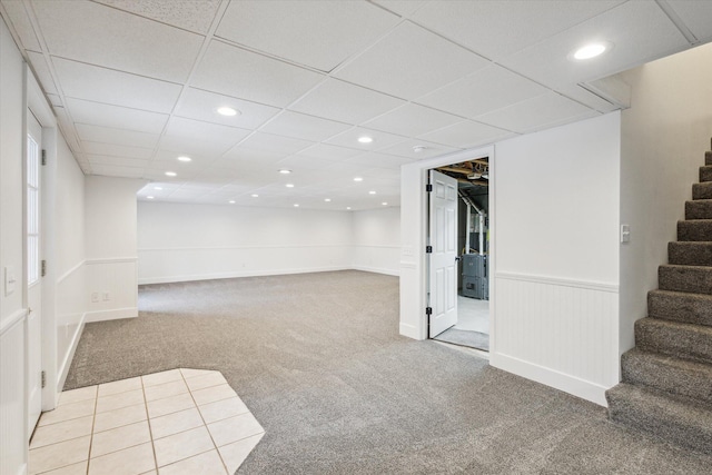 basement with a paneled ceiling and light colored carpet