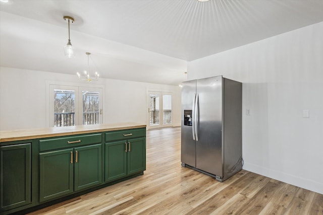 kitchen featuring pendant lighting, stainless steel fridge, light hardwood / wood-style floors, green cabinetry, and a chandelier