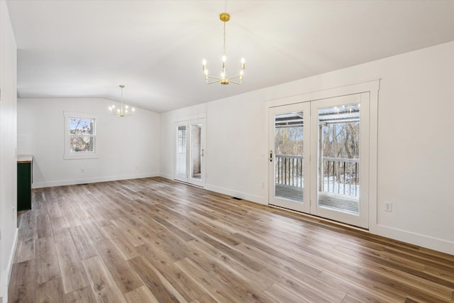 unfurnished living room with lofted ceiling, a notable chandelier, and hardwood / wood-style flooring