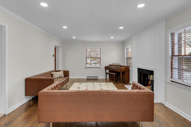 living room featuring hardwood / wood-style floors, ornamental molding, and a large fireplace