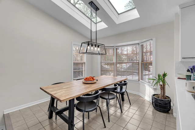 tiled dining room featuring vaulted ceiling with skylight