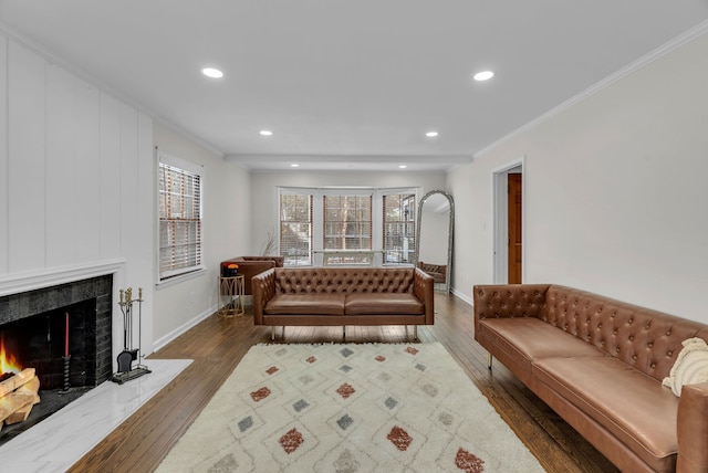 living room with dark wood-type flooring, a high end fireplace, and crown molding