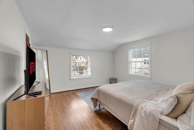 bedroom featuring multiple windows, wood-type flooring, and vaulted ceiling