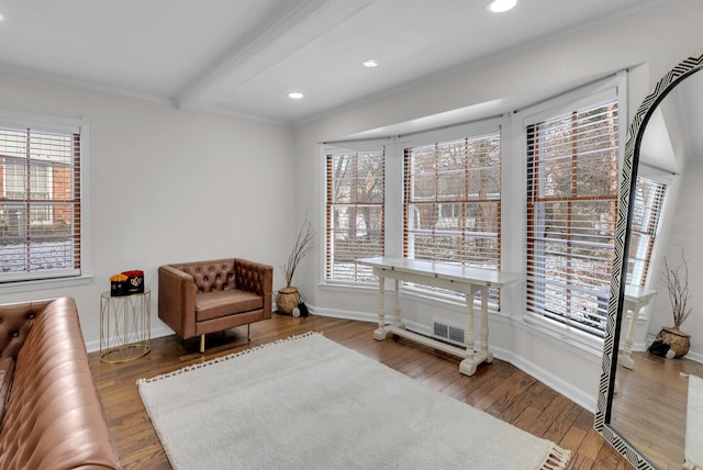 living area featuring beam ceiling, hardwood / wood-style flooring, and crown molding