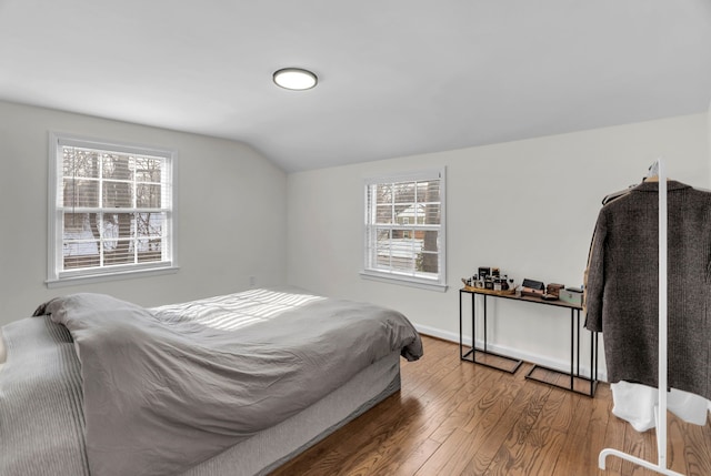 bedroom featuring multiple windows, lofted ceiling, and hardwood / wood-style floors