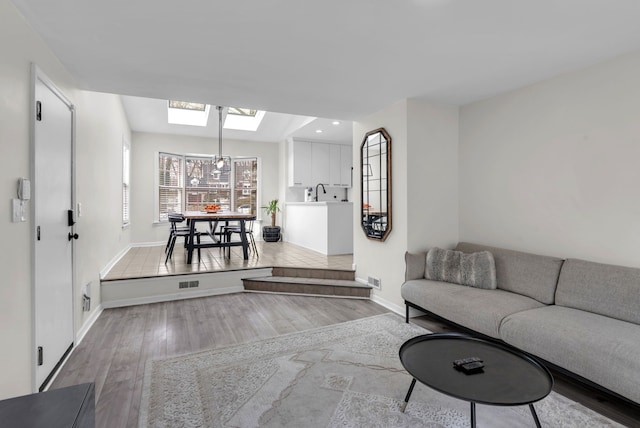 living room with light hardwood / wood-style floors and a skylight