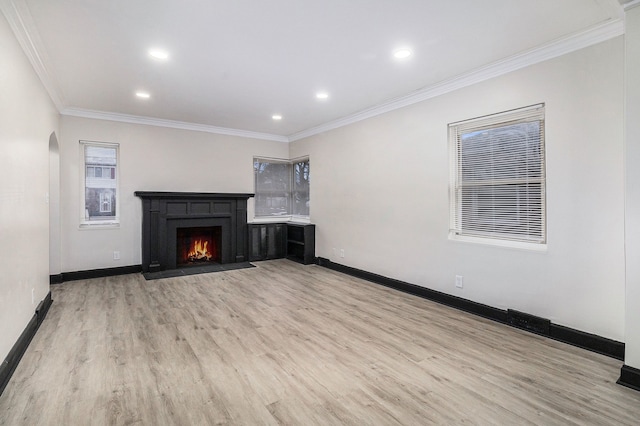 unfurnished living room featuring arched walkways, wood finished floors, a fireplace with flush hearth, and baseboards