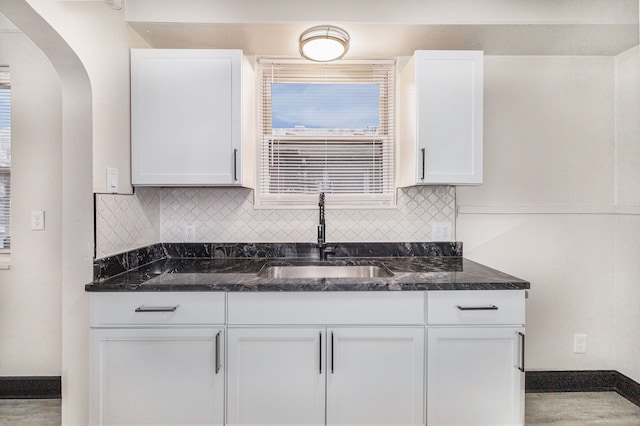 kitchen with white cabinetry, dark stone counters, and a sink