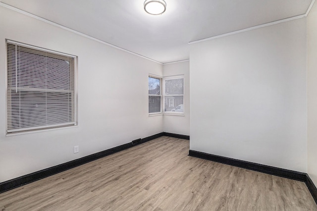 empty room featuring baseboards, crown molding, and wood finished floors