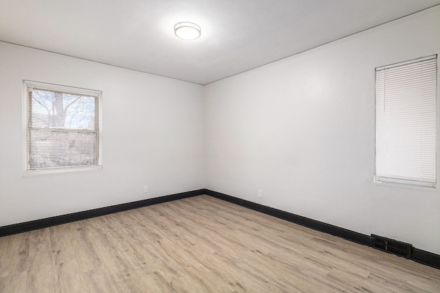 unfurnished room featuring wood finished floors, visible vents, and baseboards