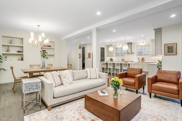 living room featuring a notable chandelier, built in features, and light hardwood / wood-style floors