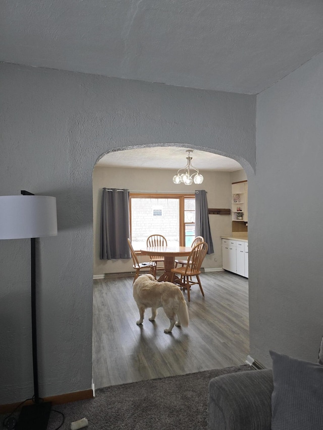 dining space with arched walkways, baseboards, a textured wall, and light wood finished floors