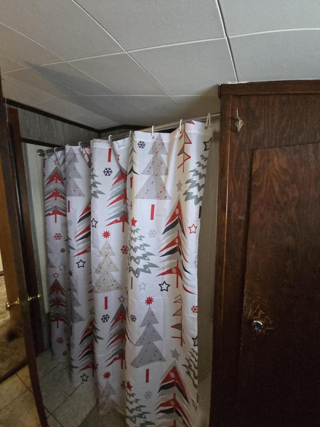 interior details with a shower with curtain and a drop ceiling