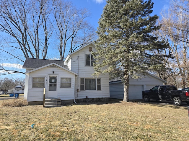 traditional-style home featuring an outbuilding, a front lawn, a detached garage, and entry steps