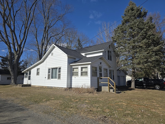 view of side of home with a garage, a lawn, and roof with shingles