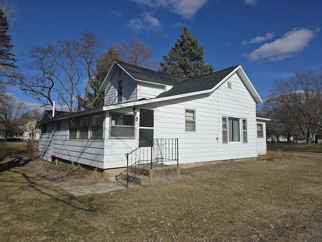 view of front of home with a shingled roof and a front lawn