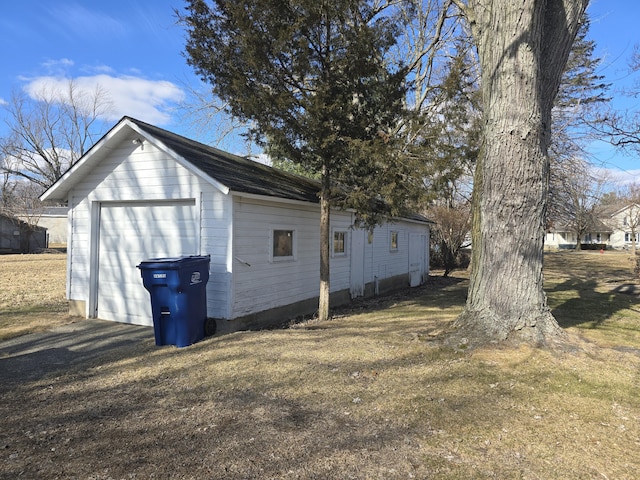 view of side of home featuring a garage, an outbuilding, and a yard