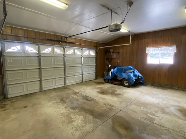 garage featuring a garage door opener and wood walls