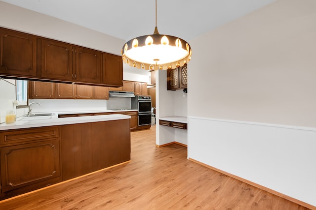 kitchen featuring pendant lighting, sink, light hardwood / wood-style floors, and black appliances