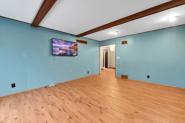 empty room with beamed ceiling and light wood-type flooring