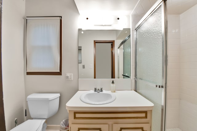 bathroom with vanity, a shower with shower door, and toilet