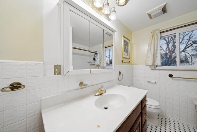 bathroom featuring vanity, plenty of natural light, tile walls, and toilet