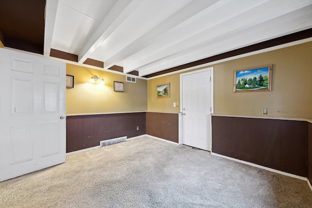 carpeted empty room featuring wooden walls and beam ceiling