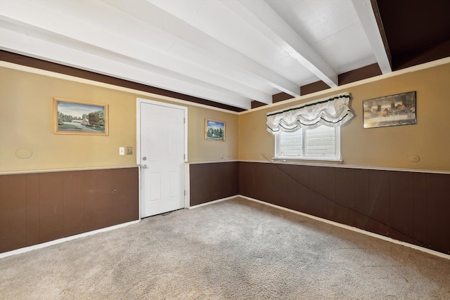 carpeted empty room with wooden walls and beam ceiling