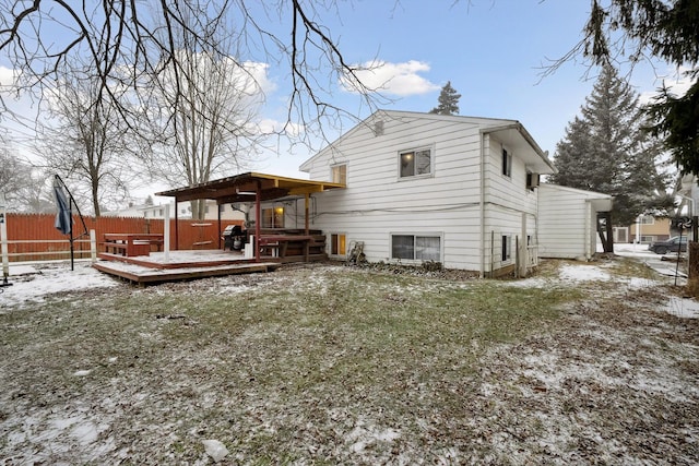 snow covered property with a wooden deck and a lawn