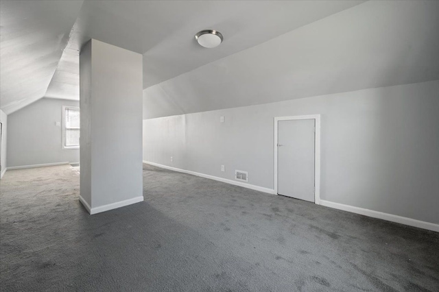 additional living space featuring vaulted ceiling and dark colored carpet