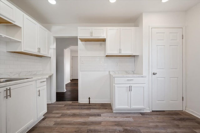 kitchen featuring light stone counters, decorative backsplash, dark wood-type flooring, and white cabinets