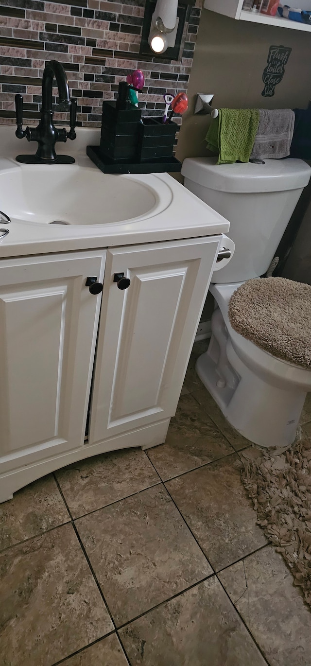 bathroom featuring vanity, decorative backsplash, and toilet