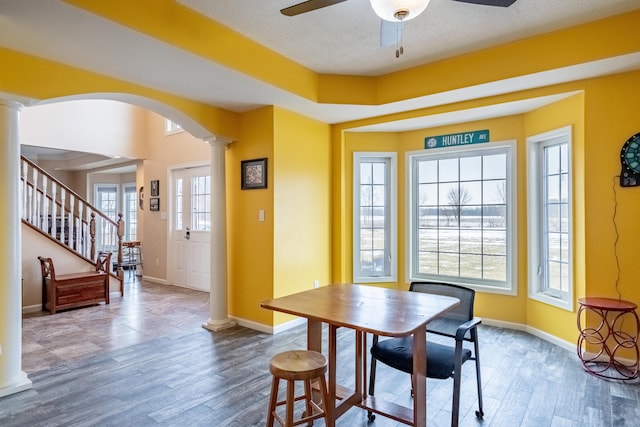 dining space featuring hardwood / wood-style flooring, a textured ceiling, ceiling fan, and ornate columns