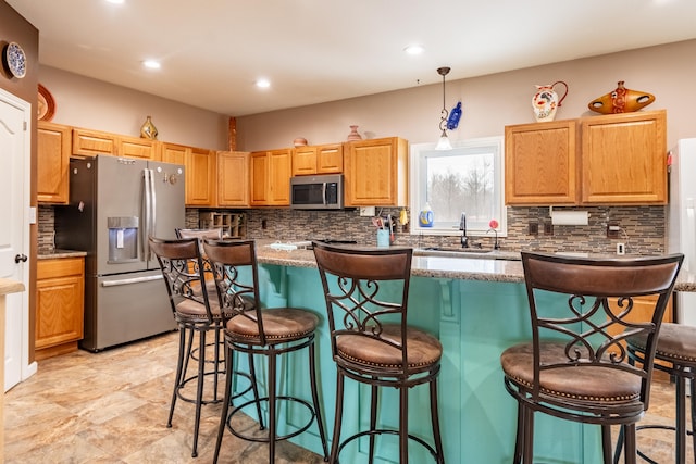 kitchen with sink, stainless steel appliances, a center island, tasteful backsplash, and a kitchen bar