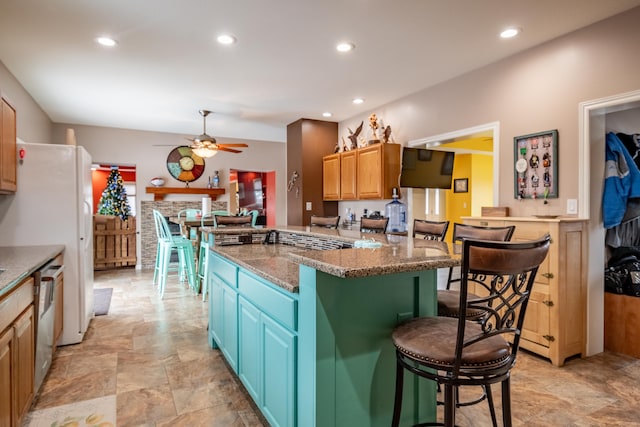 kitchen featuring stone countertops, a breakfast bar area, a center island, stainless steel dishwasher, and ceiling fan