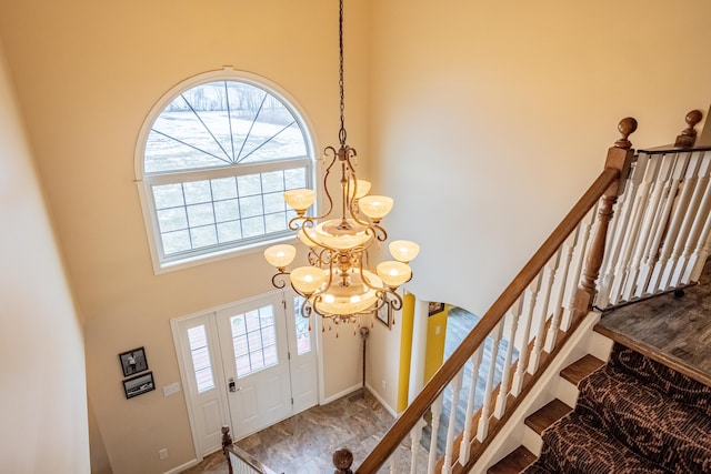 entryway with an inviting chandelier and a towering ceiling