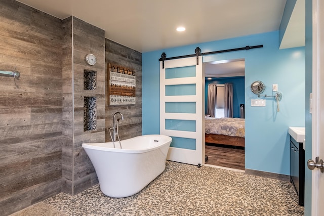 bathroom featuring a tub to relax in, vanity, and tile walls