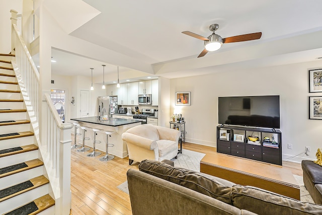 living room with light hardwood / wood-style floors and ceiling fan