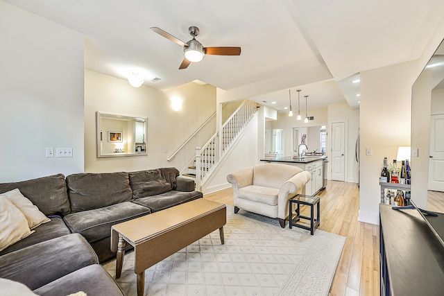 living room featuring ceiling fan, sink, and light wood-type flooring