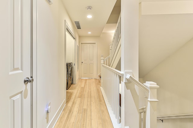 hall with washing machine and dryer and light hardwood / wood-style floors