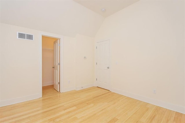 unfurnished room featuring lofted ceiling and hardwood / wood-style floors