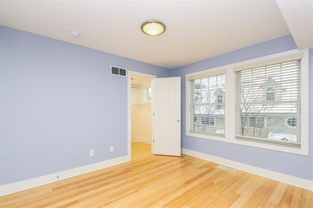 unfurnished bedroom with a walk in closet, hardwood / wood-style floors, and a closet