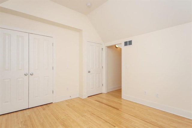 unfurnished bedroom featuring hardwood / wood-style flooring and vaulted ceiling