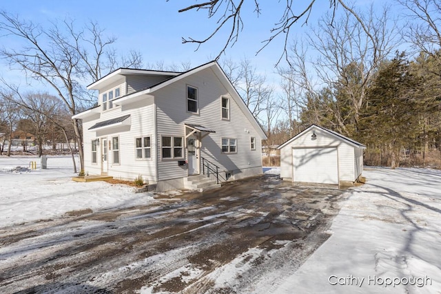 snow covered property with a garage and an outdoor structure